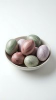 Marble-textured Easter eggs in pastel colors arranged in ceramic bowl on white background for spring holiday decorations and seasonal crafts.