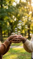 Hands catching floating soap bubbles in sunny park with golden bokeh light creating magical moment for wellness and mindfulness concepts.
