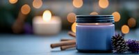 Aromatic spa candle in glass jar with cinnamon sticks and dried lavender against soft bokeh lights creating peaceful ambiance for wellness and relaxation.