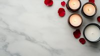 Glowing candles and red rose petals arranged on white marble background, creating romantic spa atmosphere. Copy space for wellness and beauty content.