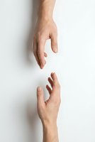 Two hands reaching toward each other against white background symbolizing connection, help, support, teamwork and human interaction for business concepts.