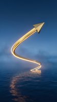 Golden glowing arrow pointing upward with curved path over calm water against blue sky, symbolizing growth, success, and positive business direction.