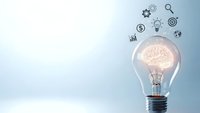 Light bulb with glowing brain inside surrounded by business icons representing innovation, creativity and strategic thinking for corporate solutions.