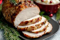 Juicy roasted turkey breast sliced on black plate, seasoned with herbs and spices, garnished with fresh rosemary and cranberries, festive holiday dinner setting.