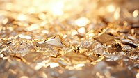 Crumpled gold foil texture with soft focus bokeh effect creates luxurious metallic background with shimmering highlights and reflective surface detail.