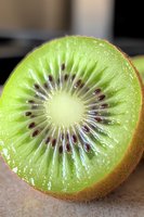 Fresh juicy kiwi fruit cut in half showing detailed cross section with bright green flesh, white center and black seeds in radial pattern. Macro photography.