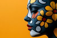 Female profile with creative face art featuring yellow sunflower design and silver dots on dark skin against vibrant orange background, showcasing artistic makeup and body painting.