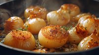 Caramelized onions sizzling in cast iron pan with herbs and butter, golden brown with charred edges for rich flavor in gourmet cooking.