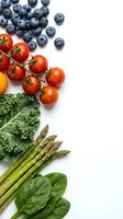 Fresh organic vegetables and berries arranged on white background with copy space for healthy eating and nutrition concepts.