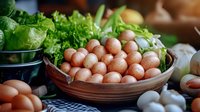 Fresh brown eggs in rustic ceramic bowl with green lettuce and garlic on kitchen table. Natural organic farm produce for healthy cooking and meal preparation.