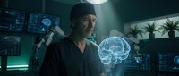 Middle-aged male surgeon examining holographic brain projection in futuristic medical facility with advanced technology displays and monitoring equipment.