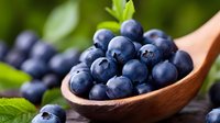 Fresh ripe blueberries in wooden spoon with green leaves on natural background for healthy eating and organic food concepts.