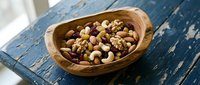 Mixed nuts and dried fruits in a rustic wooden bowl on a weathered blue table, a wholesome snack concept for healthy eating and nutrition.