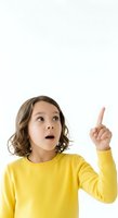 Young girl with shoulder-length brown hair wearing bright yellow long-sleeve shirt, pointing upward with surprised expression against white background, isolated for design use.