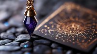 Mystical purple crystal pendant with copper details resting on tarot card with golden sun pattern against dark stone background, creating magical atmosphere.
