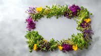 Colorful frame made of fresh microgreens, sprouts, and edible flowers on light gray background, creating natural border for food presentation.