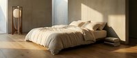Minimalist bedroom interior with low-profile bed, neutral bedding, wooden floor, and warm natural light streaming through large windows for modern home design projects.