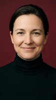 Professional middle-aged Caucasian woman in black turtleneck smiling warmly at camera against burgundy background for corporate headshots and business portraits.