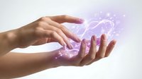 Hands creating magical purple energy with sparkling light effects and glowing particles floating between palms on white background.