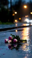 Pink and purple roses lying on wet asphalt at night with bokeh lights reflecting in rain puddles, creating romantic melancholic atmosphere.