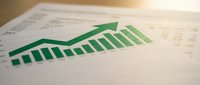 Green bar chart showing upward growth trend on financial spreadsheet with data analysis for business reporting and market performance evaluation.