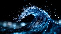 Dynamic blue water wave curling with splashing droplets against dark background, dramatic lighting creates glowing bokeh effect and highlights liquid motion.