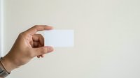 Hand holding blank white card against neutral background, suitable for business branding, corporate identity mockups, and professional presentations.