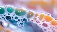 Colorful soap bubbles with vibrant green and orange hues floating on water surface creating abstract pattern for cleaning and hygiene concepts.