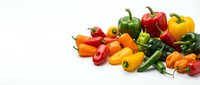 Fresh colorful bell peppers in red, yellow, orange and green varieties arranged on white background for cooking and healthy eating concepts.