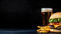 Fresh cheeseburger with french fries and cold draft beer on dark background. Classic fast food composition with copy space for menu or advertising.