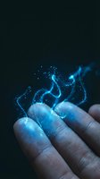 Human hand with glowing blue electric energy sparks and lightning bolts emanating from fingertips against dark background for digital art concepts.