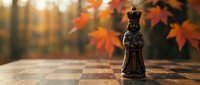 Black chess king piece on wooden board with vibrant autumn foliage background creating warm strategic game atmosphere for business leadership concepts.