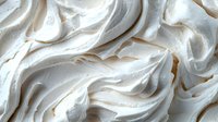 Creamy white meringue texture with soft peaks and swirls, creating a light and airy dessert topping for pies, cakes, and pastries.