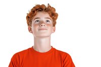 Young teen with ginger curly hair wearing bright orange t-shirt looking up with hopeful expression against white background, isolated portrait for advertising.