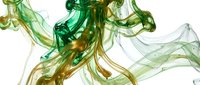 Flowing green and gold liquid ink swirls create an abstract artistic composition on isolated white background, suitable for design projects.