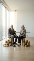 Senior business partners sitting on golden coin stacks in modern office discussing financial success and wealth management strategies.