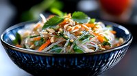 Fresh Asian glass noodle salad with colorful vegetables and herbs in decorative blue bowl, healthy meal ready to serve for restaurant menu or cookbook.