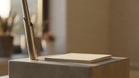 Minimalist workspace with open book and brass desk lamp on wooden surface creating warm ambient lighting for reading and study.