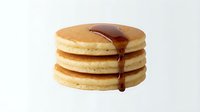 Stack of golden pancakes with maple syrup dripping down the sides, perfect for breakfast, brunch, and food advertising projects.