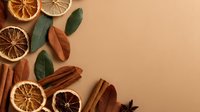 Dried citrus slices, cinnamon sticks, star anise and bay leaves arranged on beige background, creating natural aromatic composition for seasonal decor or culinary use.