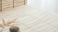 Zen meditation space with bamboo mat, natural shadows and stone creating peaceful minimalist atmosphere for wellness and relaxation practices.