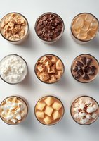 Nine glass bowls filled with various dessert toppings including chocolate chips, caramel cubes, whipped cream and nuts arranged in grid pattern on white background.