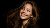 Young Caucasian woman with flowing brown hair and bright genuine smile against dark background, natural beauty portrait with windswept hair effect and warm lighting.