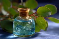 Small glass bottle with blue liquid and cork stopper against blurred green leaves background, magical potion concept for wellness and aromatherapy designs.