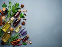 Essential oils in glass bottles with fresh herbs and spices on textured background for aromatherapy, natural wellness and spa treatments.