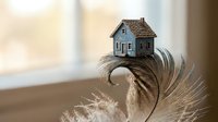 Miniature house model balanced on delicate feather creating dreamy home ownership and real estate investment concept for mortgage and property dreams.