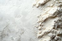White flour scattered on textured surface, creating contrast between smooth background and powdery mounds for baking preparation.