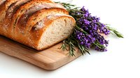 Fresh sliced artisan bread loaf on wooden cutting board with sprigs of lavender and rosemary herbs, rustic food styling on white background.