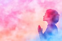 African American woman with curly hair silhouette praying against pink and blue ethereal background, expressing spirituality, faith, and inner peace in meditative pose.