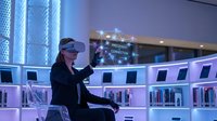 Professional businesswoman using virtual reality headset in modern futuristic office environment with blue lighting and advanced technology setup.